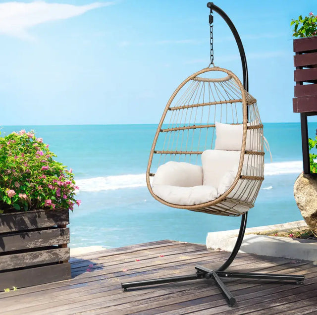 White egg-shaped hanging chair on a freestanding support outdoors