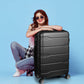 Black Slimbridge suitcase shown beside a seated traveller