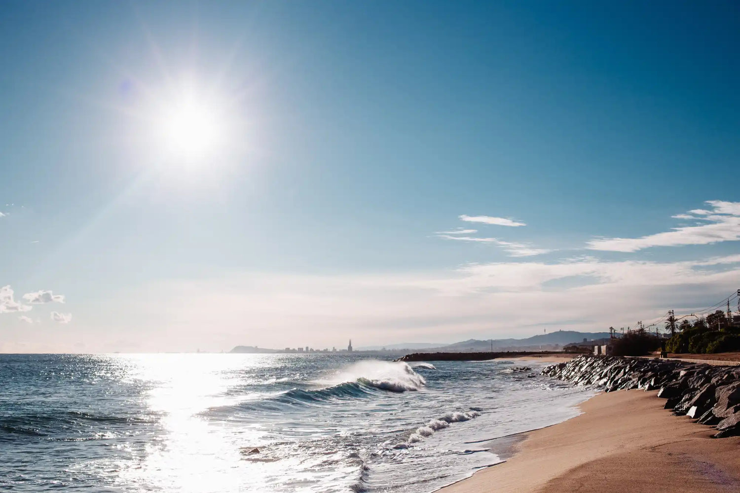 A sunny beach with waves crashing on the shore.